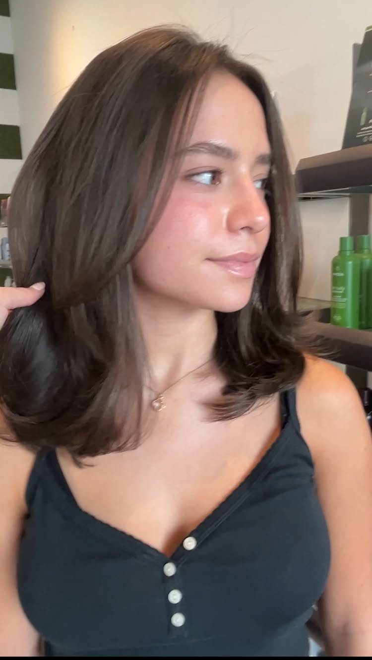 Woman showing a dark brown shoulder-length lob with softly curved ends
