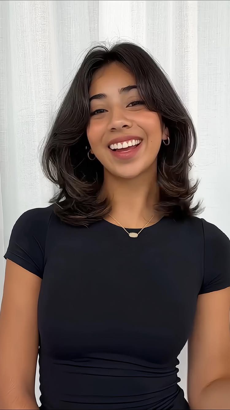 Woman with dark feathered shoulder-length layers and outward-curving ends