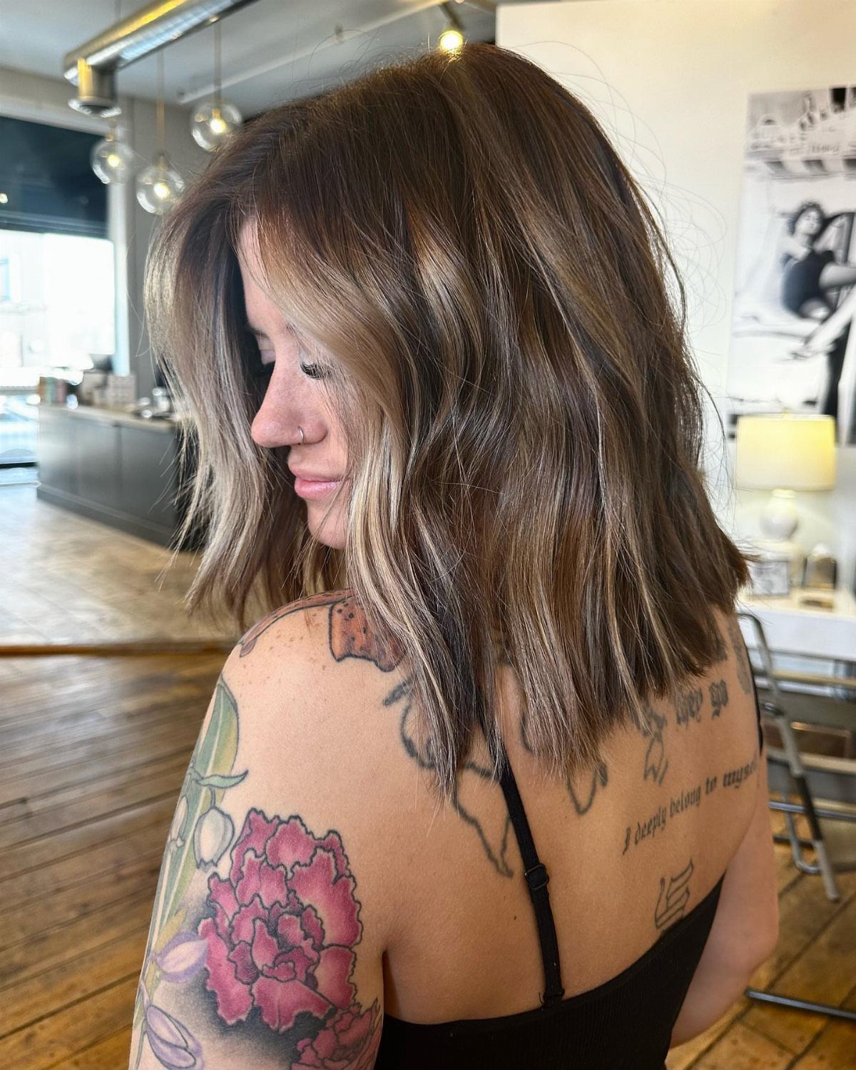 Woman showing a dark, layered textured lob in a bright hair salon