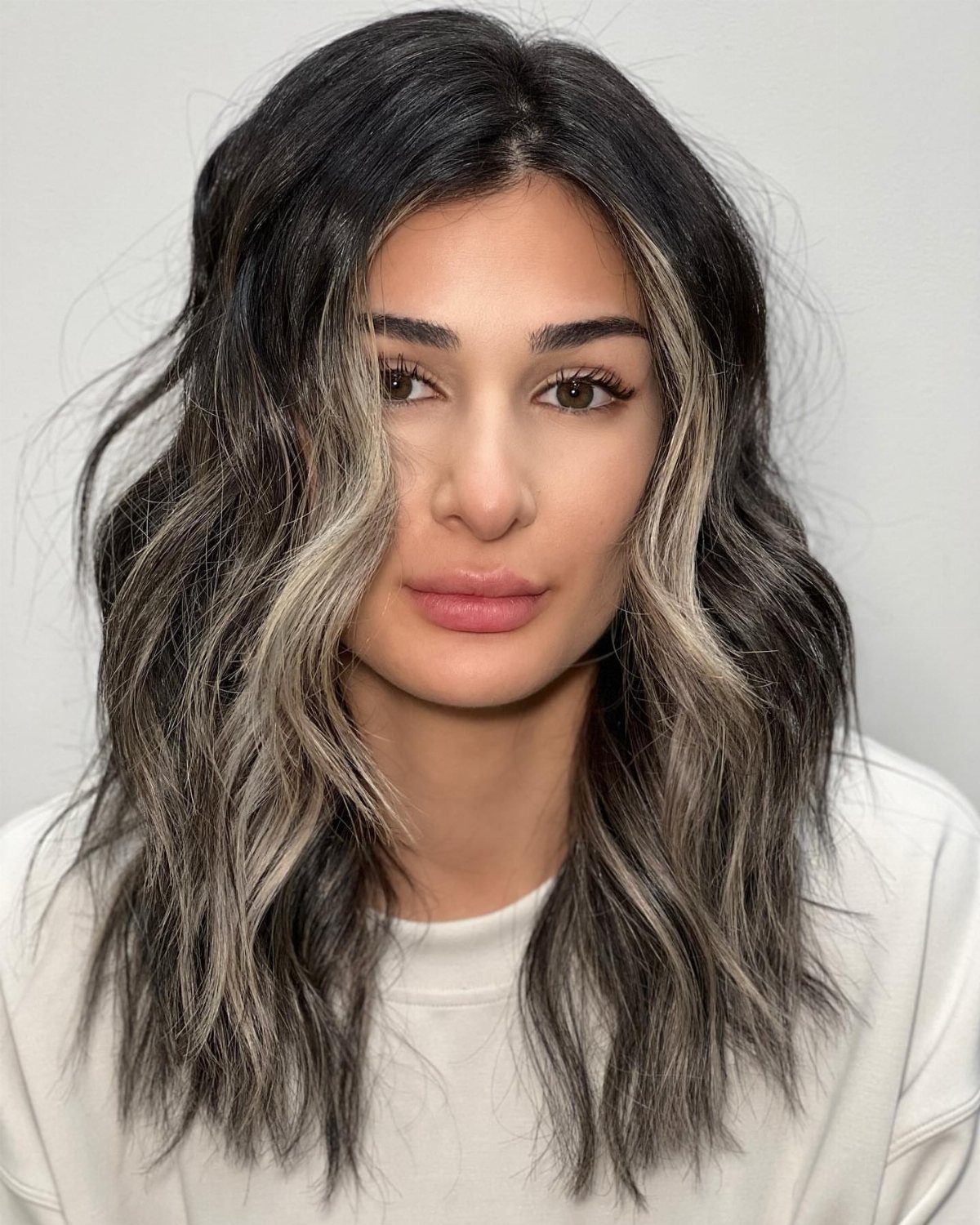 Woman with center-parted shoulder-length layers and face-framing balayage highlights