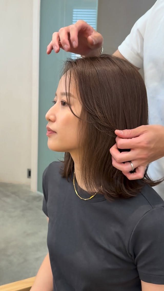 Woman with straight shoulder-length hair having it arranged in a salon