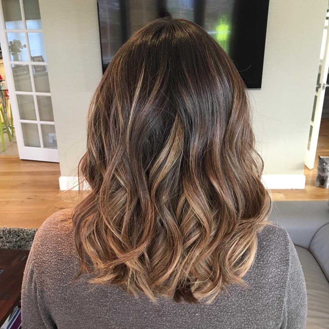Shoulder-length brown waves with golden balayage highlights from the back