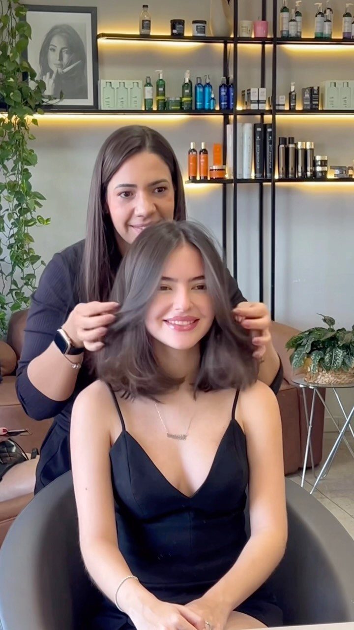 Woman displaying a smooth sleek long bob haircut in a salon