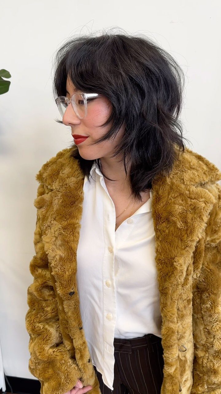 Person with a choppy, layered dark shag haircut and bangs