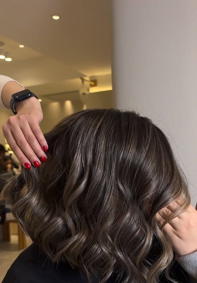 Dark shoulder-length hair styled in loose, tousled waves at a salon