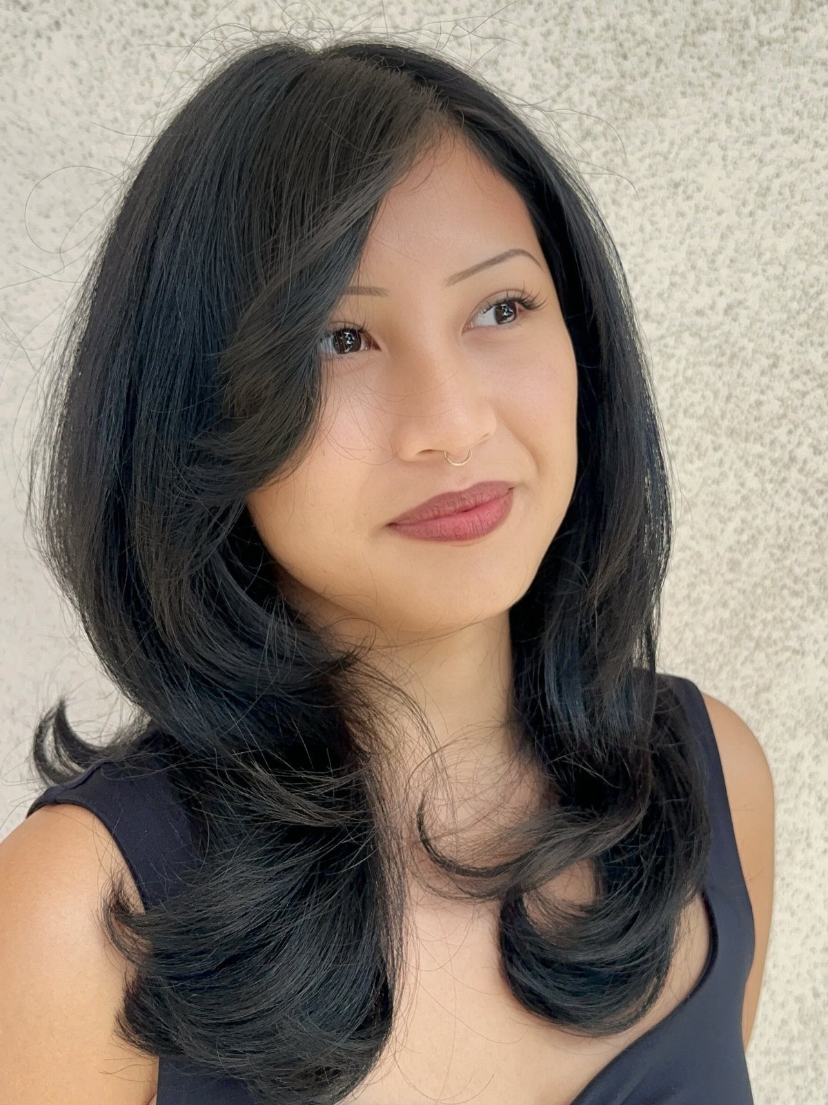 Woman with long dark layered hair styled in soft waves and curled ends