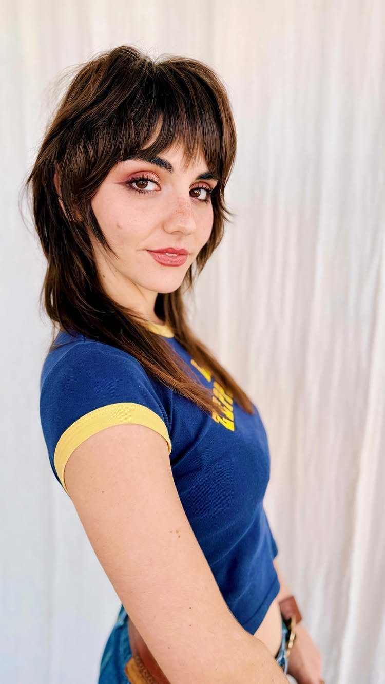 Woman with dark layered shag hair and thick straight-across bangs