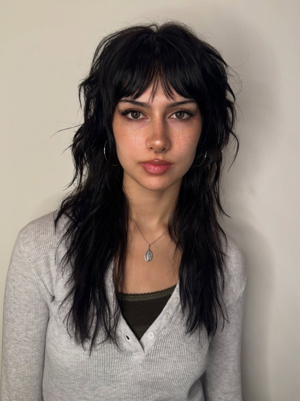 Woman with long, textured brunette shag layers and wispy bangs
