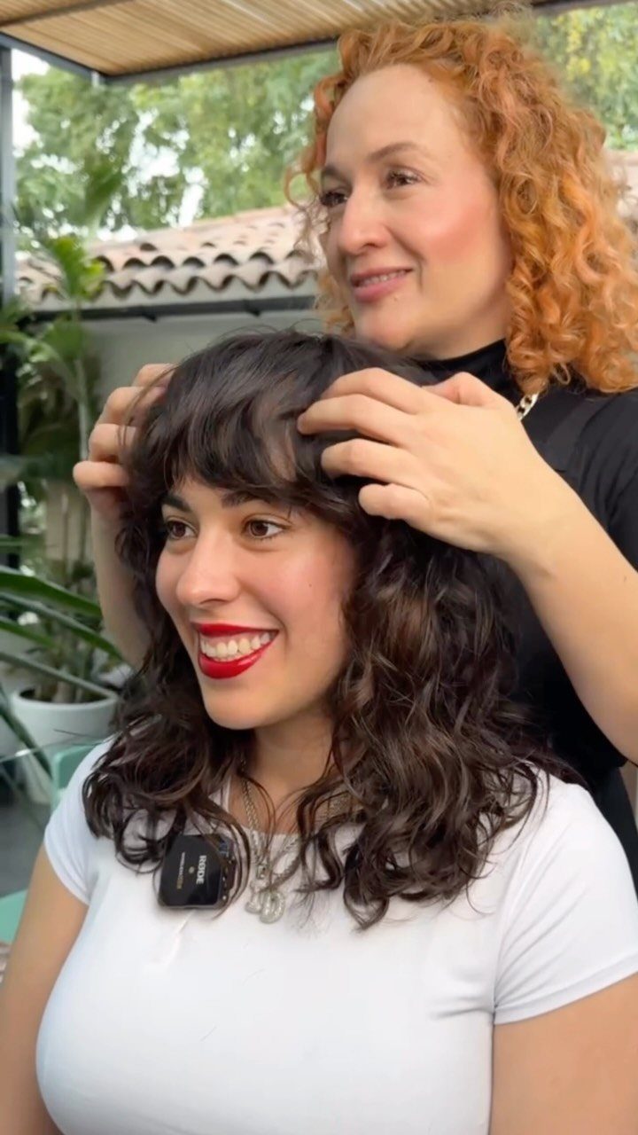 Woman with dark brown wavy shag haircut and bangs in a salon chair