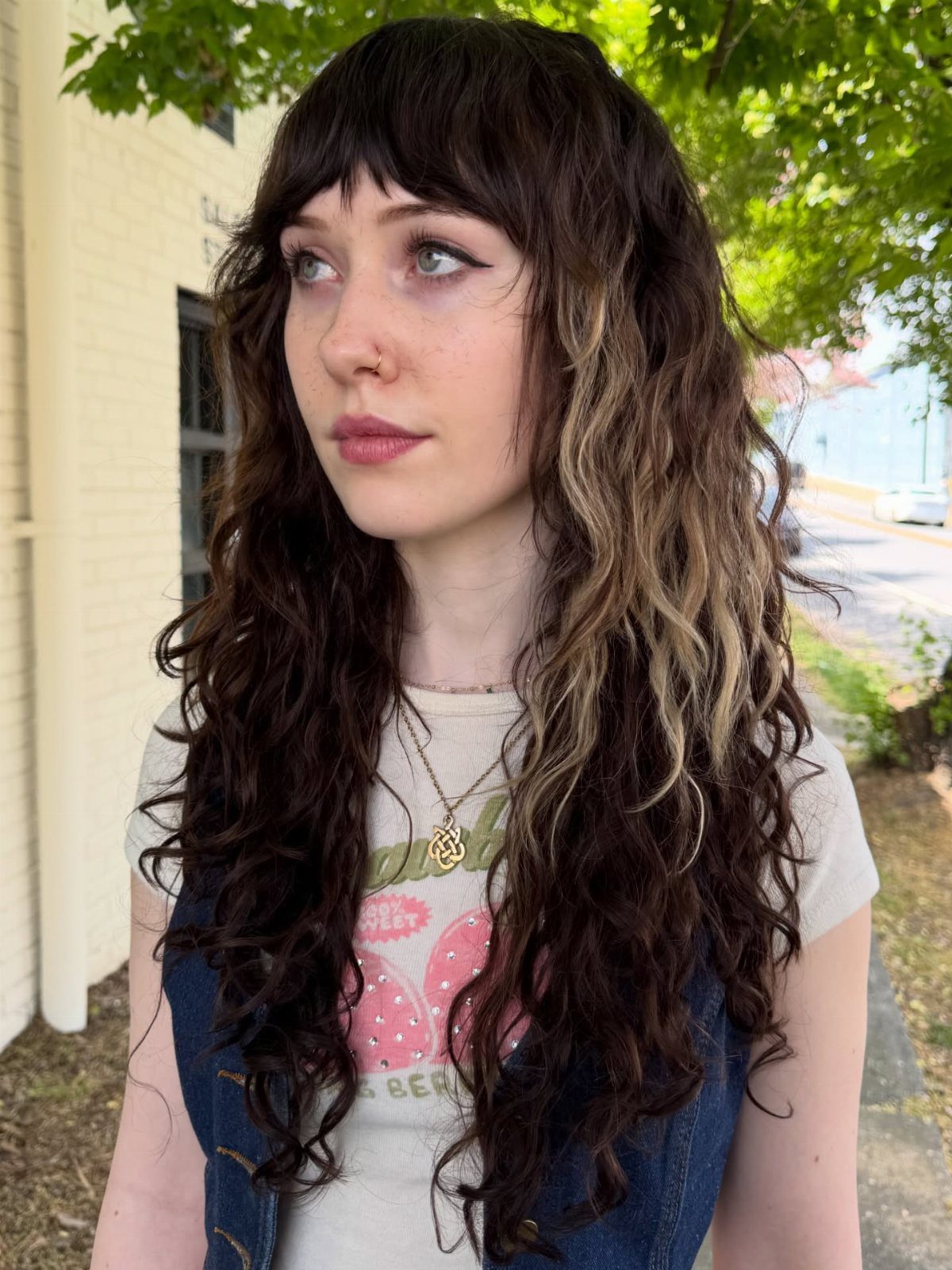 Woman with thick dark wavy shag haircut, choppy layers, bangs and lighter highlights