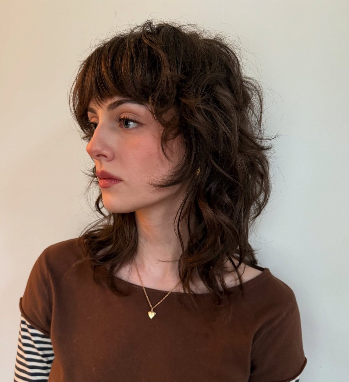 Dark brown shoulder-length shag haircut with bangs and loose, layered waves