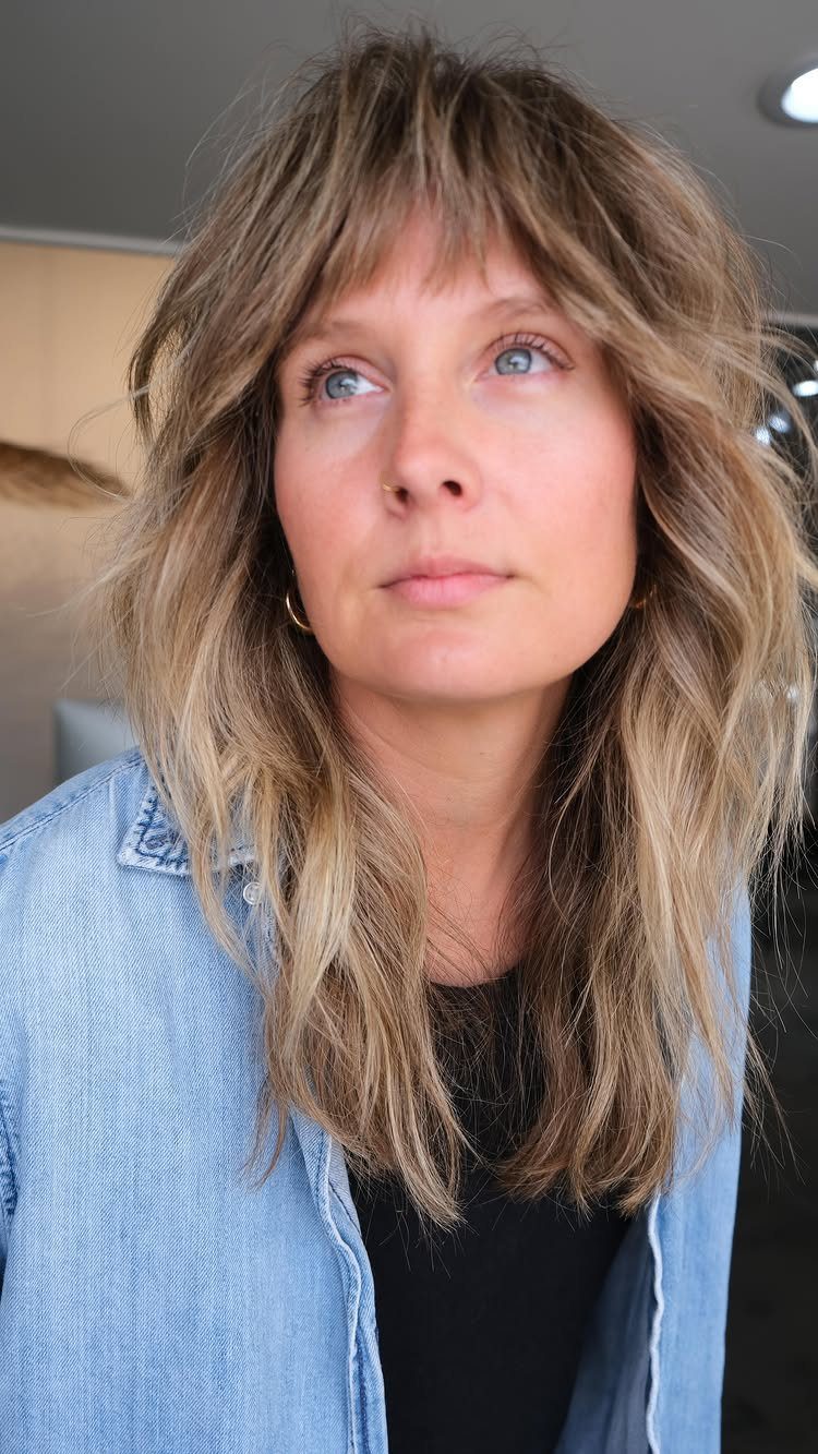 Woman with shoulder-length layered shag haircut and wispy bangs
