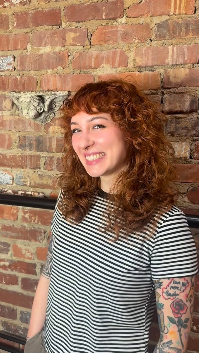 Woman with a side-curtain curly shag, auburn layers, and striped shirt