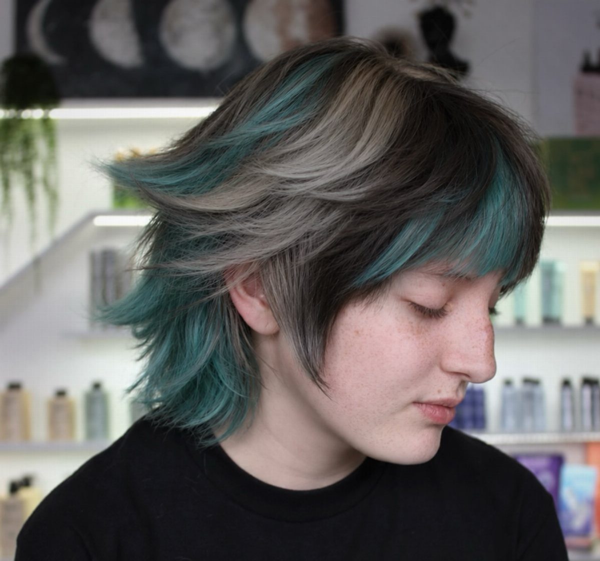 Medium shag haircut with teal and gray streaks framing a person's face