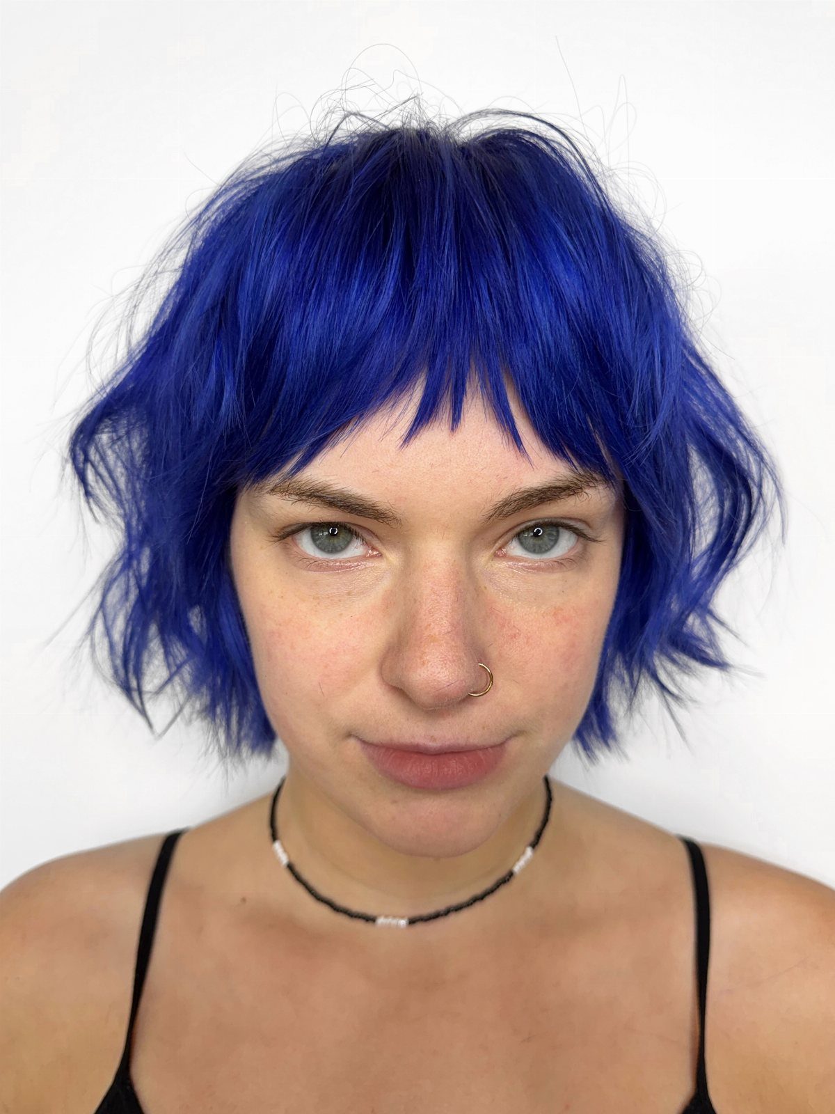 Person wearing a vivid navy-blue wavy shag haircut with choppy bangs