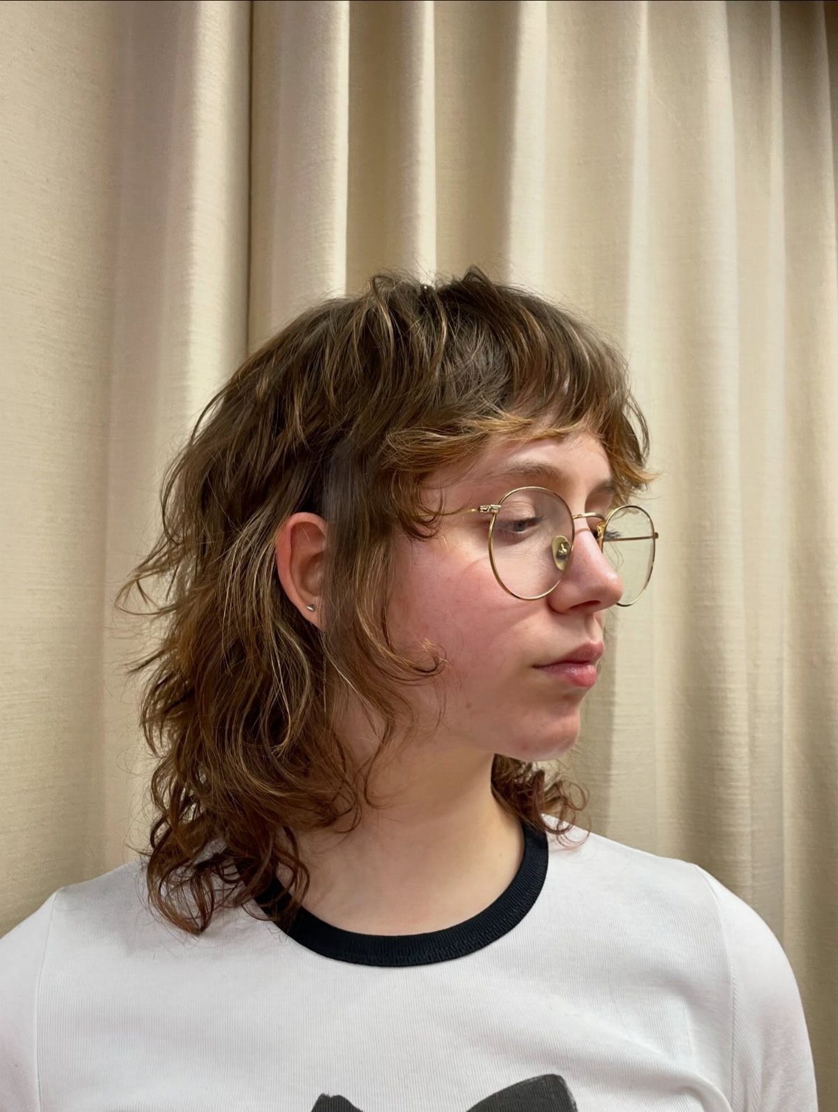 Person with medium wavy brown shag haircut and short micro bangs