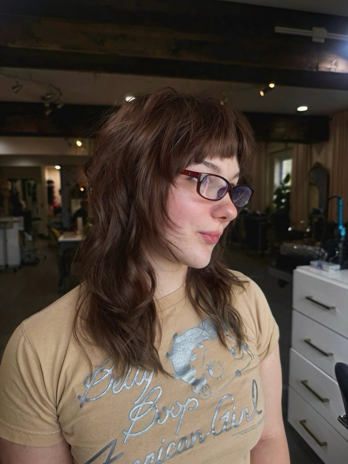 Person showing a medium brown wavy shag haircut with layered texture and short bangs
