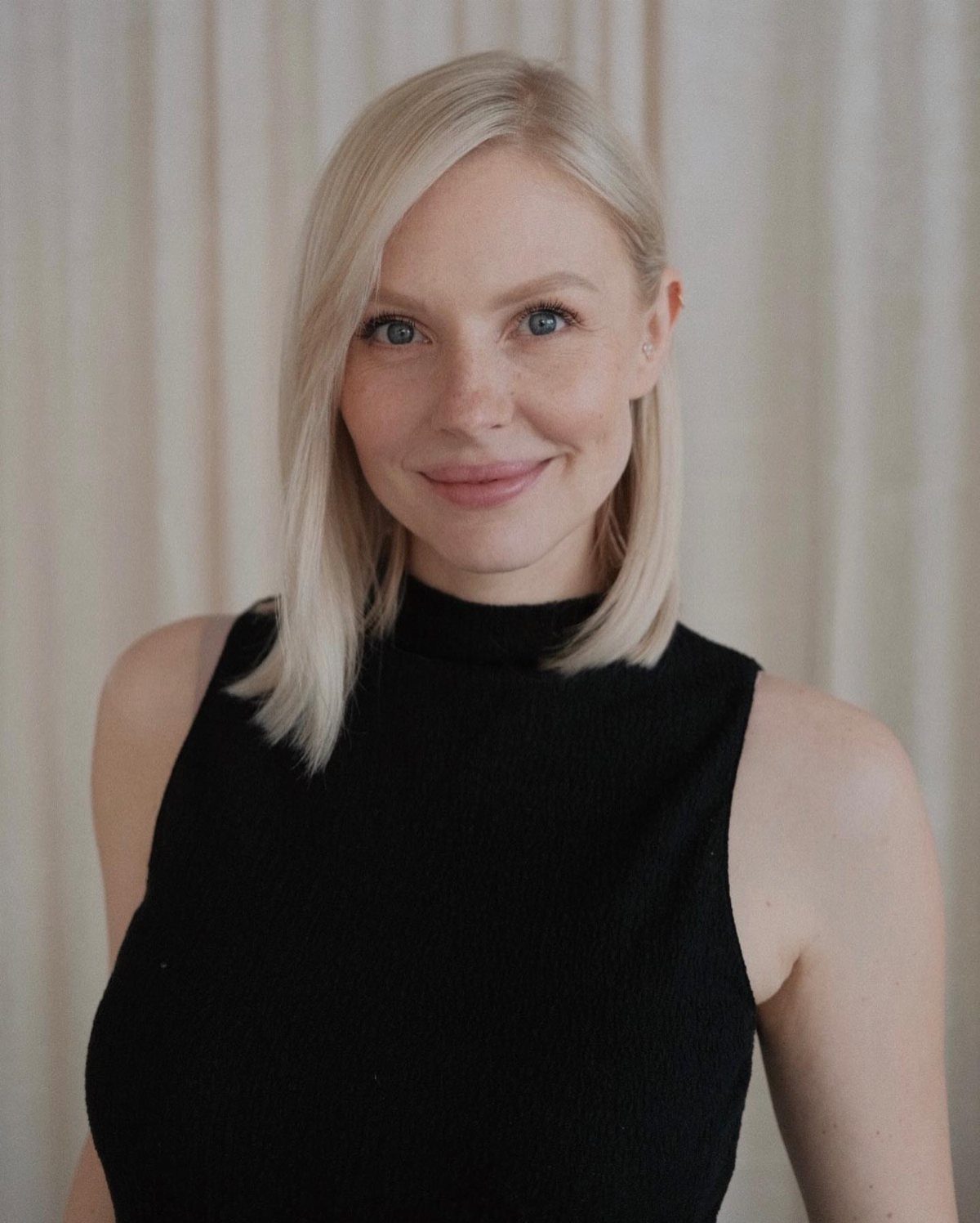 Woman with a straight shoulder-length blonde lob and a side part