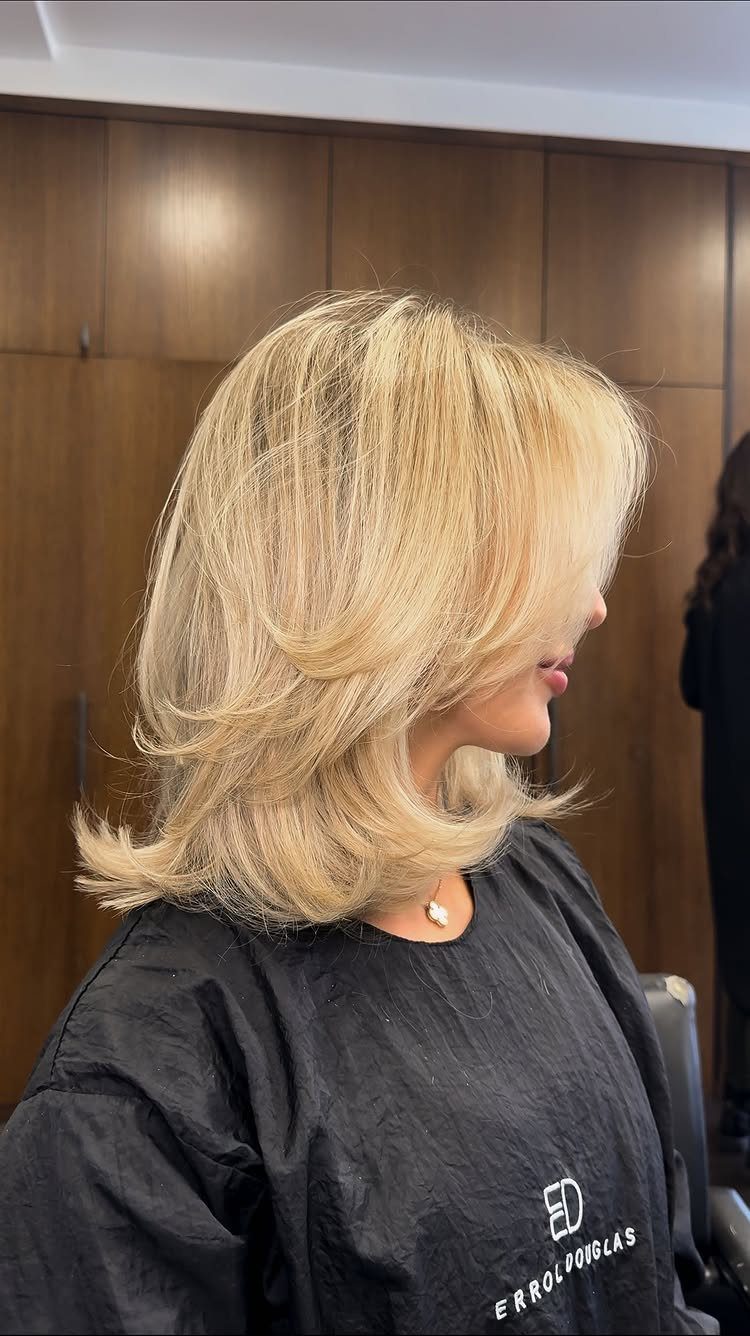 Blonde shoulder-length feathered layers with softly curled ends, shown in profile