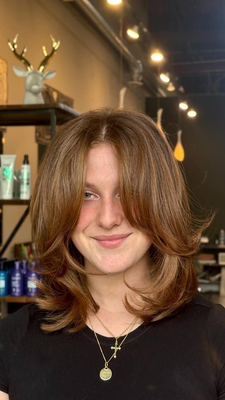 Shoulder-length layered haircut frames a person's face in a salon