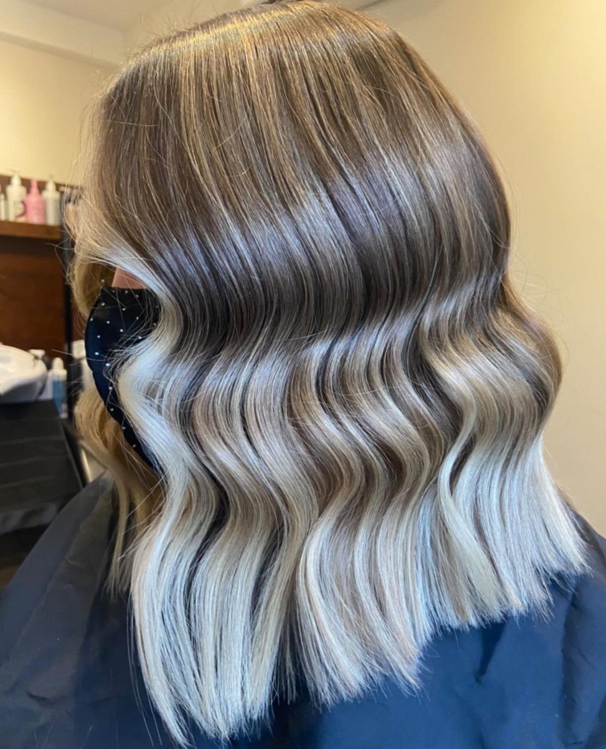 Shoulder-length silver-blonde lob with shadowed brown roots and glossy waves