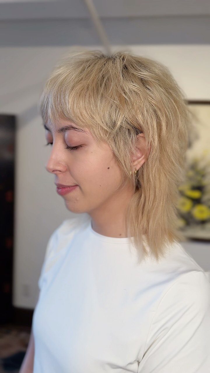 Blonde shullet with choppy layers, wispy bangs, and a longer back