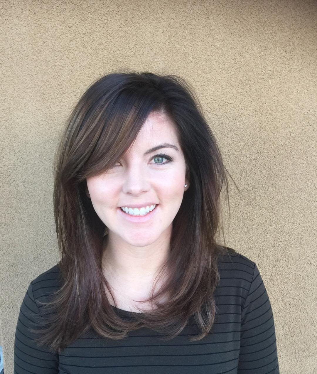 Woman with shoulder-length dark hair and long side-swept bangs