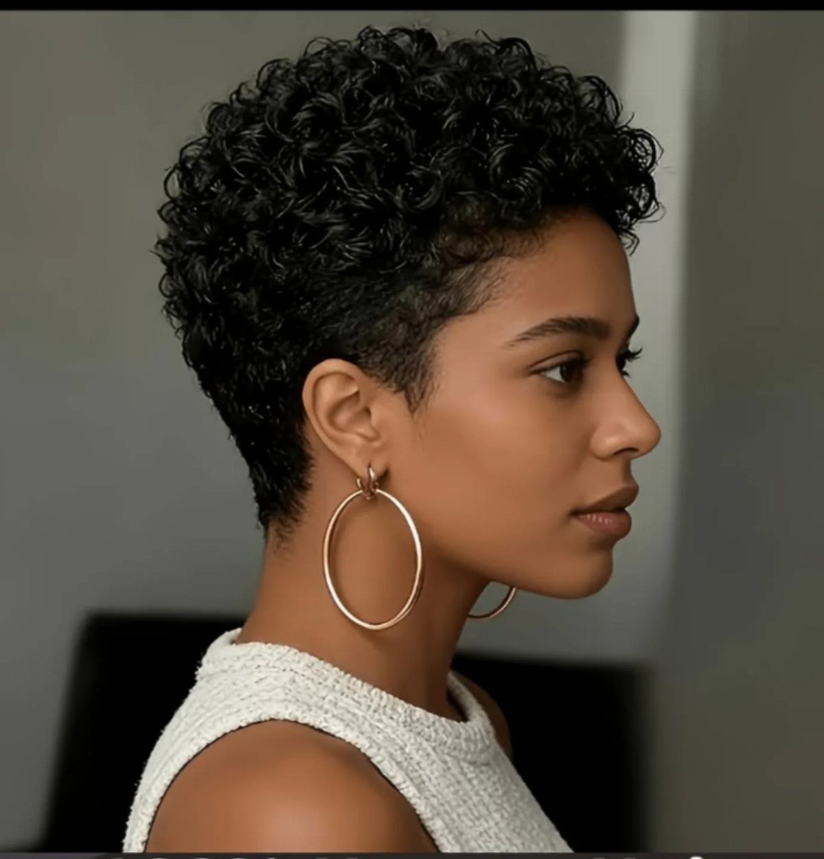 Woman with a compact short afro and large hoop earrings in profile