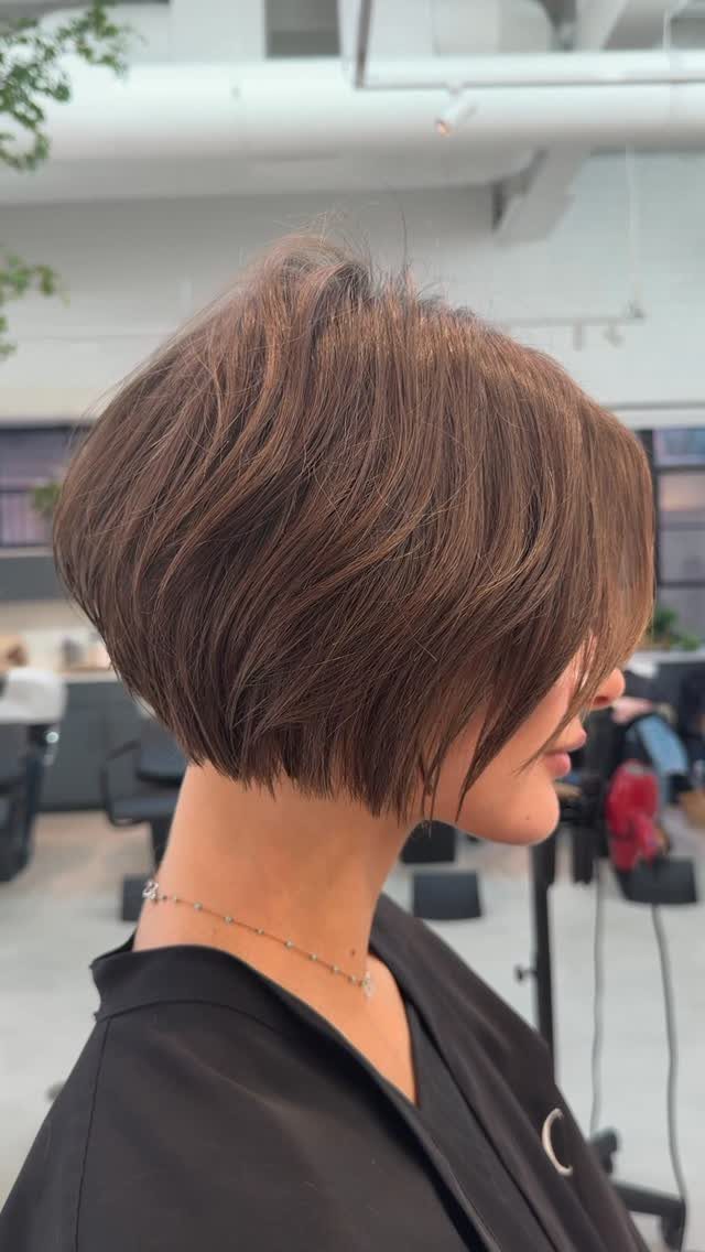 Short layered brown bob shown in profile at a bright hair salon
