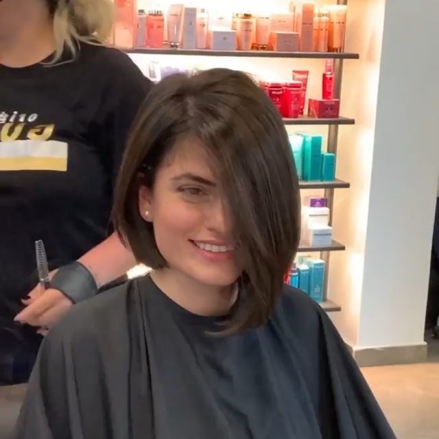 Person with a dark chin-length bob and side-swept bangs in a salon