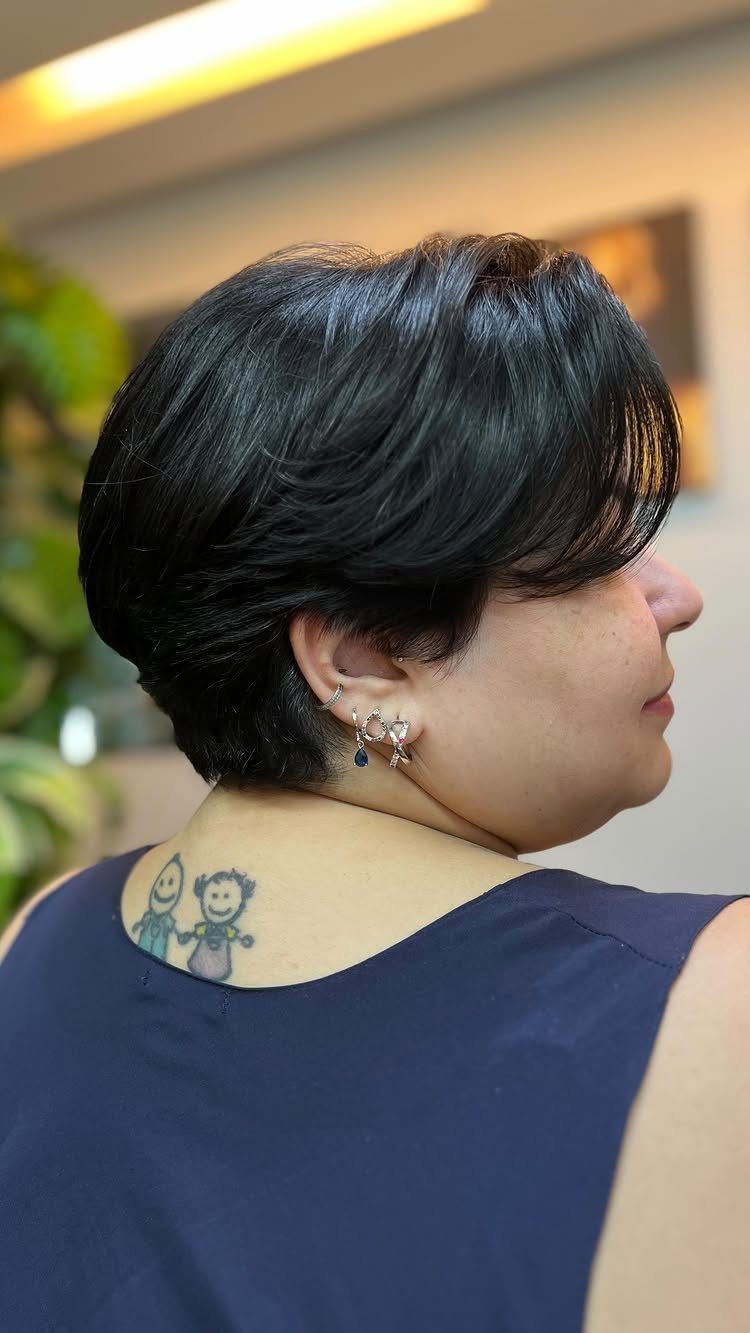 Side-swept black pixie haircut with longer layered top and short nape
