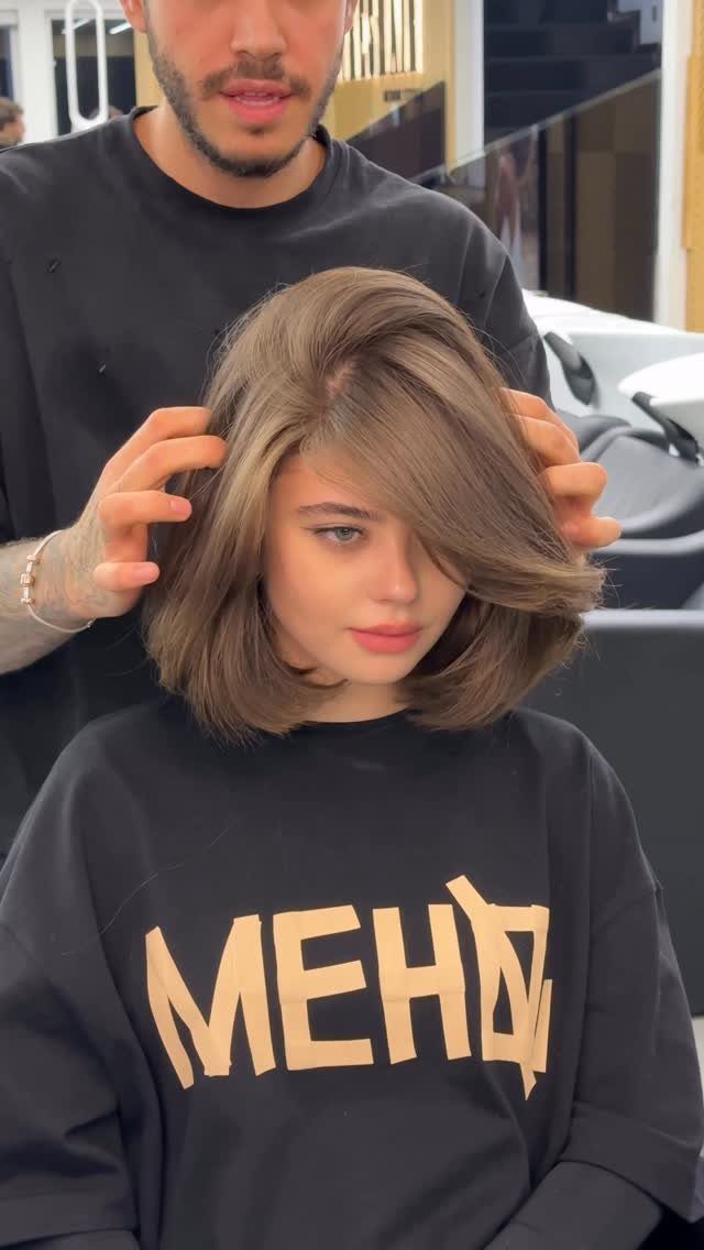 Woman showing smooth shoulder-length brown lob with side-swept front layers in a salon