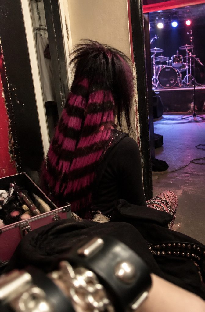 Young adult seen from behind with black and pink striped teased hair