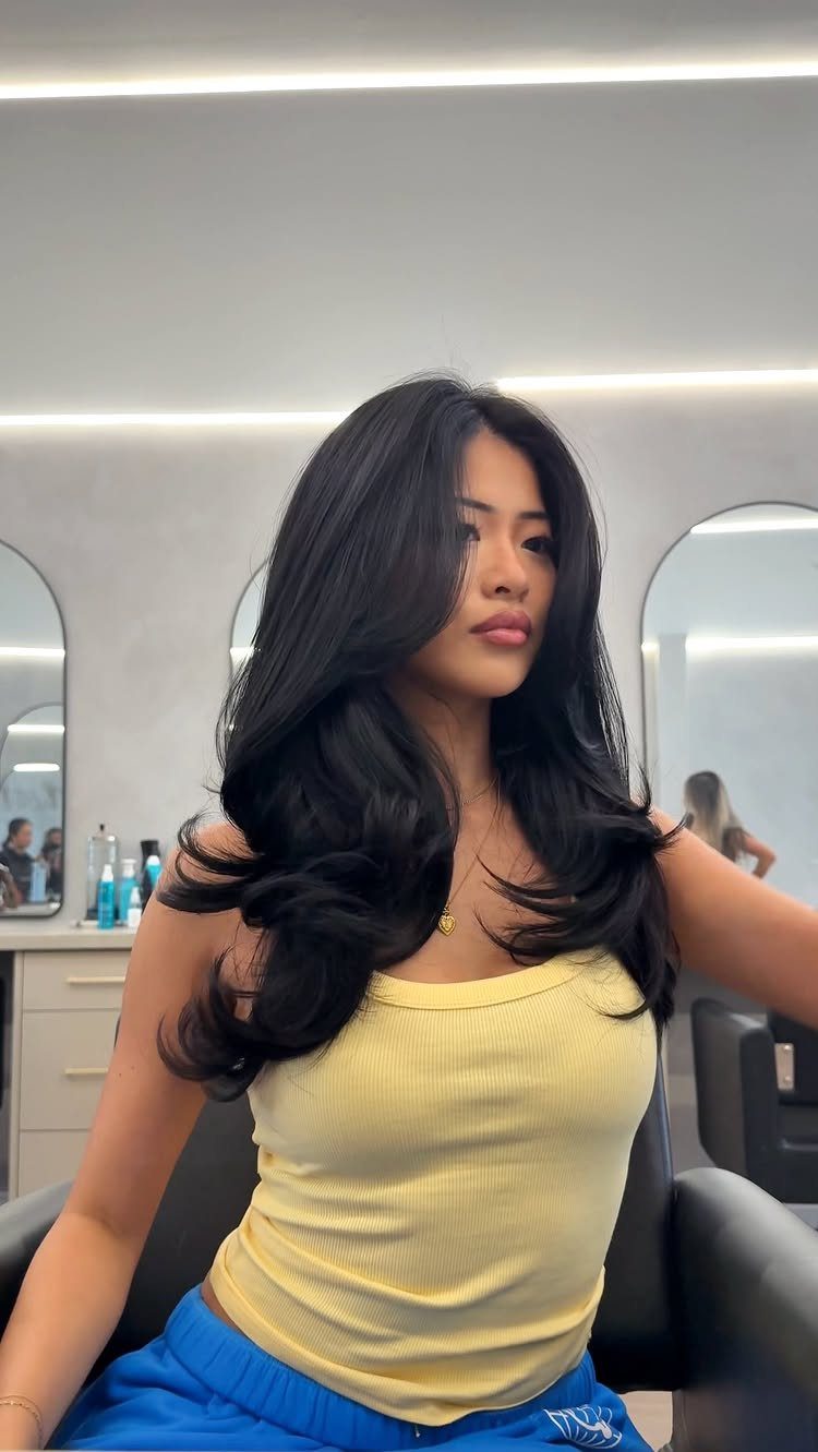 Woman showing long dark layered hair with voluminous curled ends in a salon