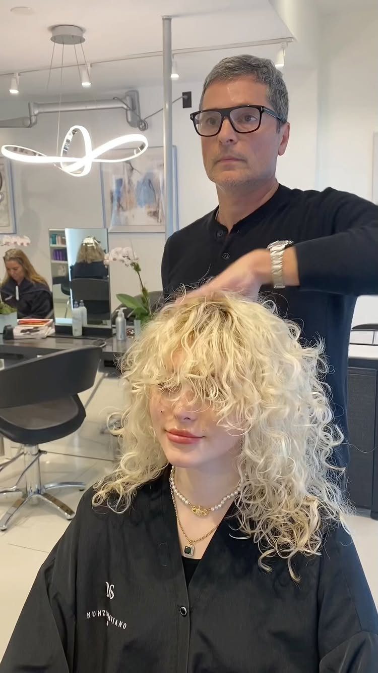 Blonde curly shag haircut with layered curls and fringe in a salon