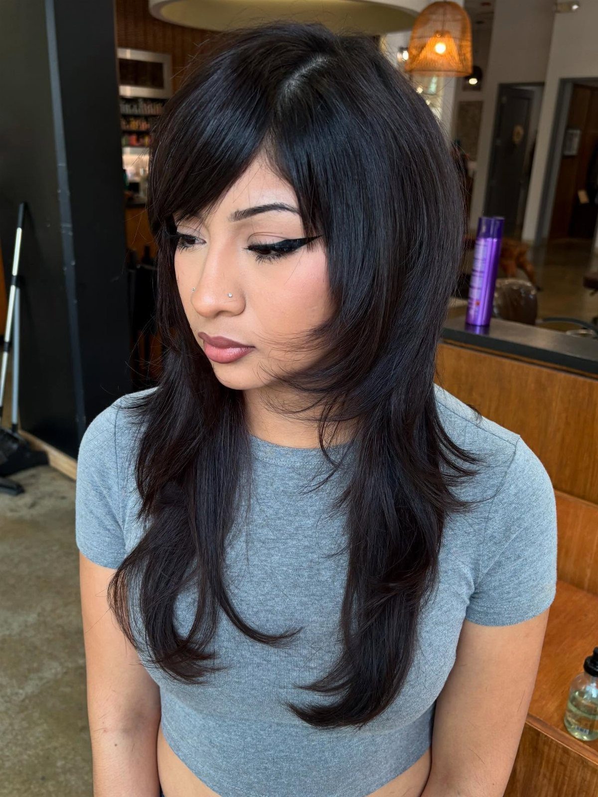Woman showing long dark shag haircut with sweeping side bangs