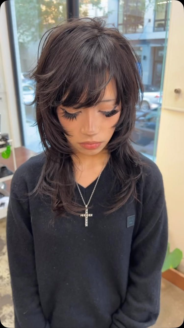 Long side-parted shag haircut with layered dark hair and sweeping fringe