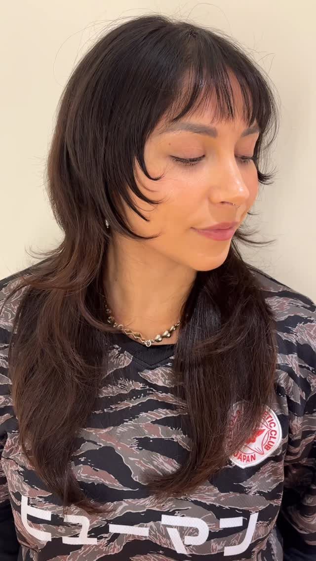 Woman showing a smooth, long layered shag haircut with wispy bangs