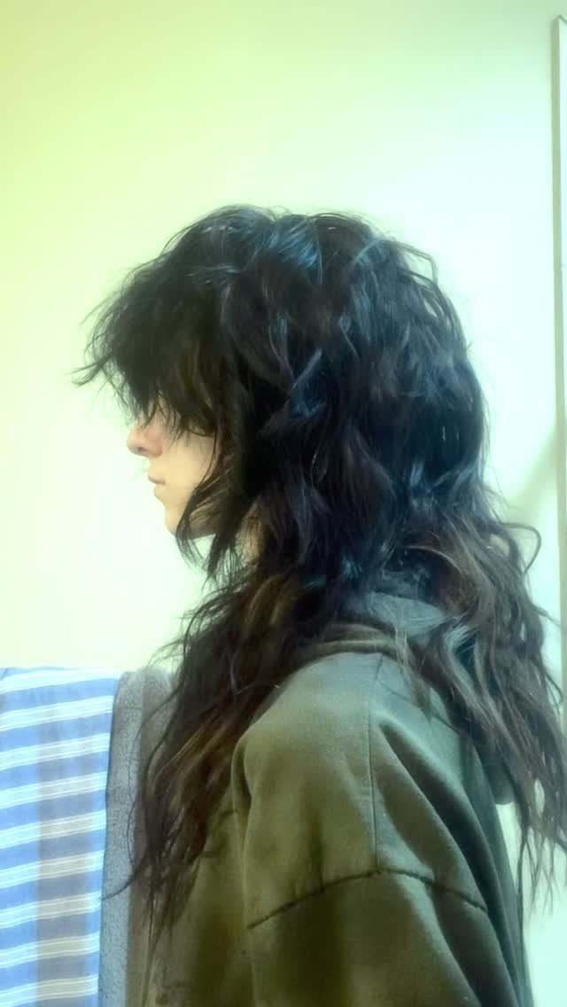 Long dark shaggy hair falls in loose waves with layered bangs