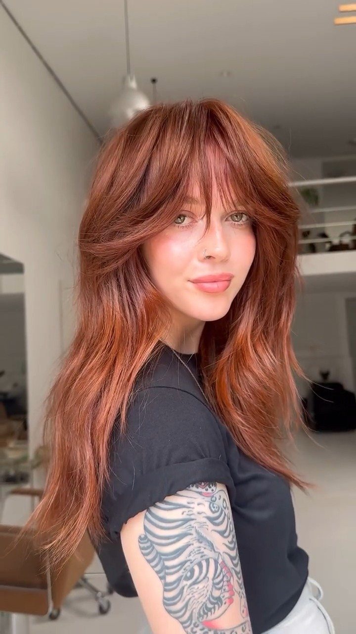 Woman showing long reddish-brown shag layers and an imperfect grown-in fringe
