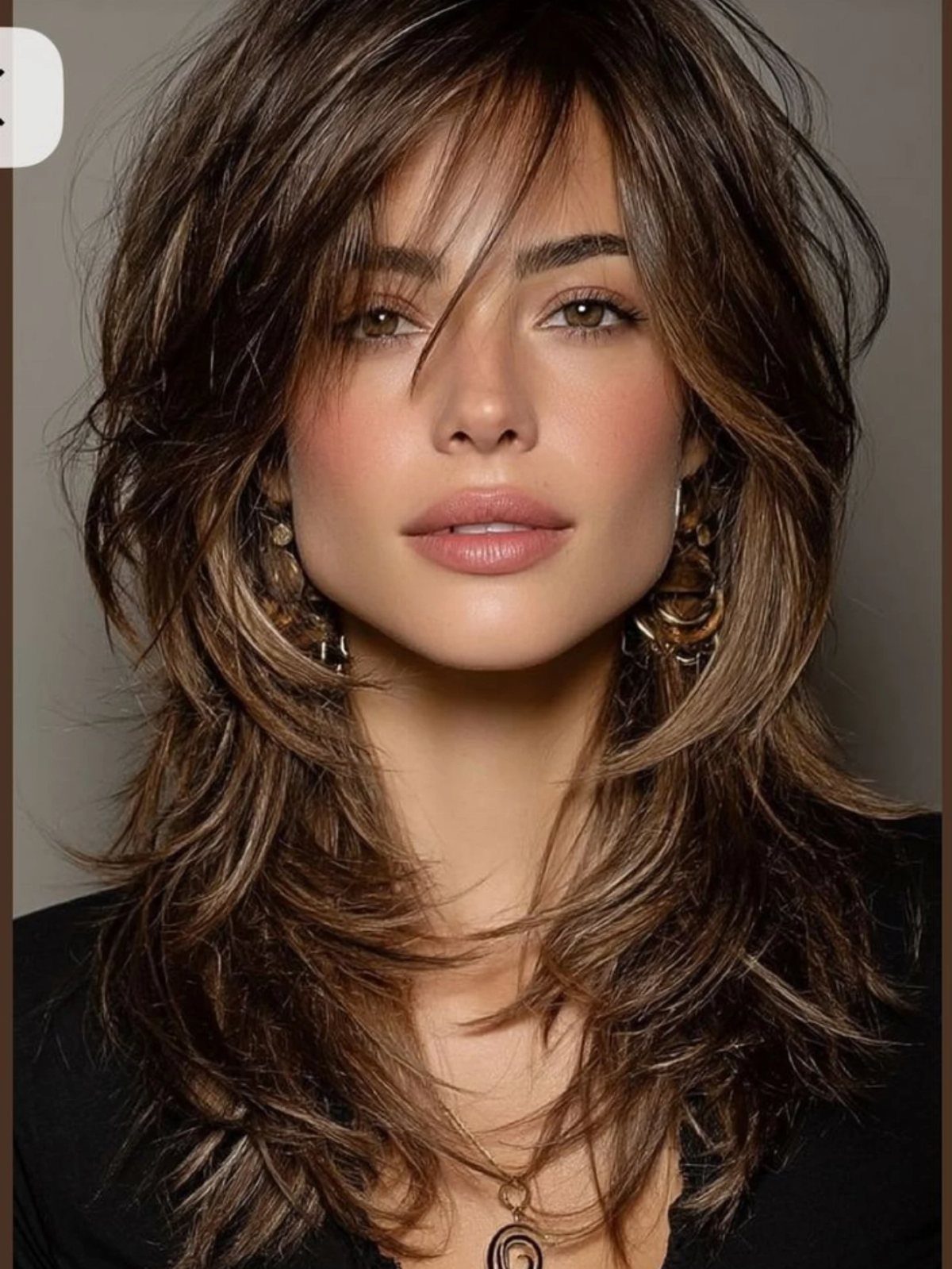 Woman with long dark brown shag, wispy bangs, and feathered layers