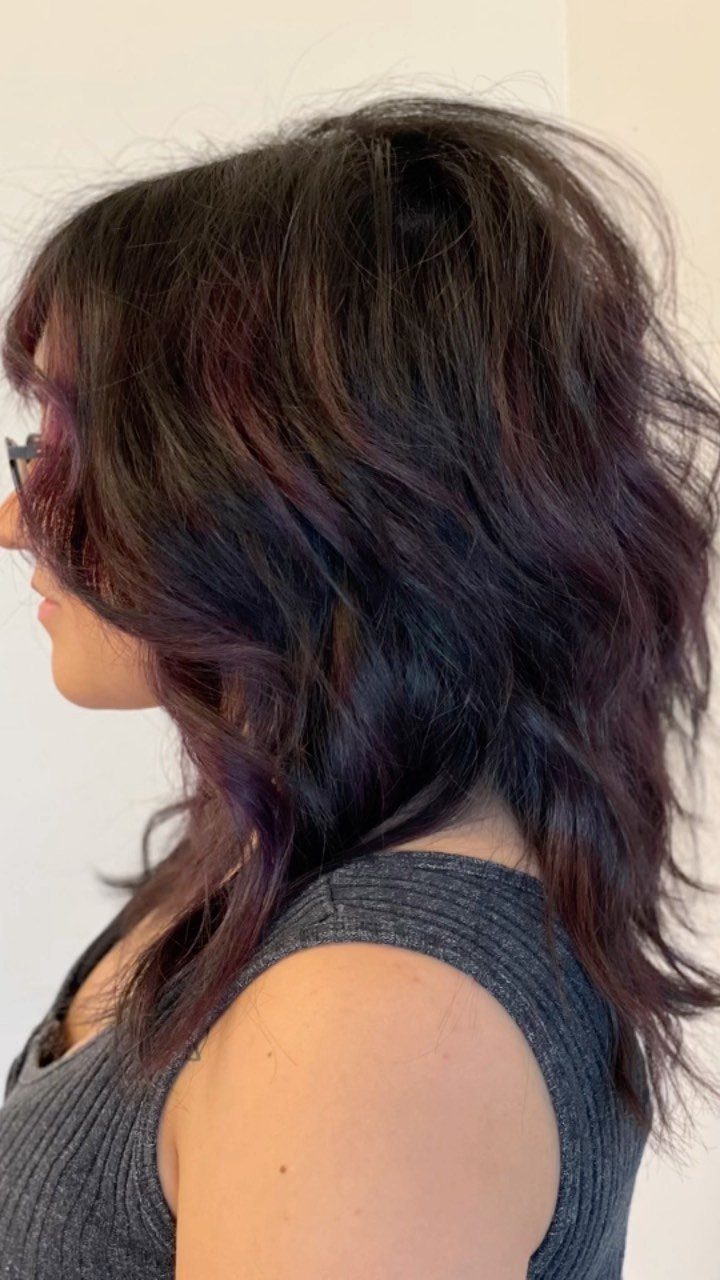 Woman with long, tousled dark shag layers and wispy face-framing pieces