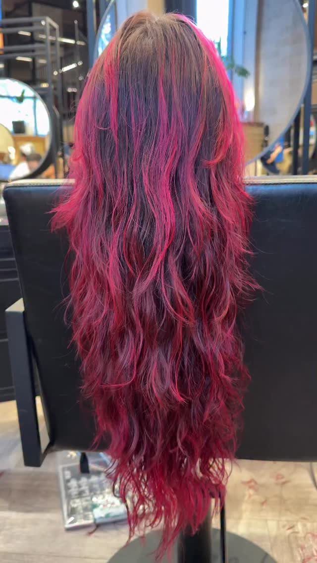 Long layered shag with vivid red and magenta color in a salon chair