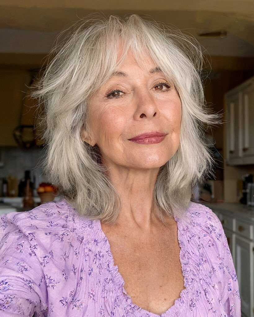 Older woman showing a layered silver shag with wispy bangs