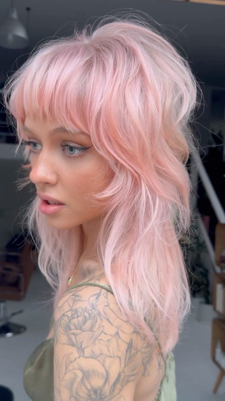 Woman with pink shaggy layers and bangs in a salon