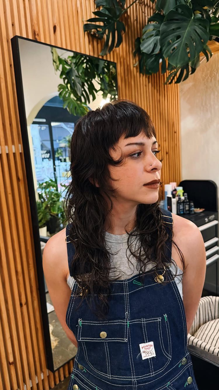 Woman shows a dark shag mullet with short fringe and longer layered back