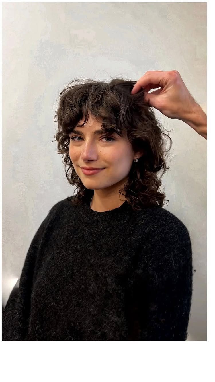 Person with short dark curly shag, layered crown, and soft bangs