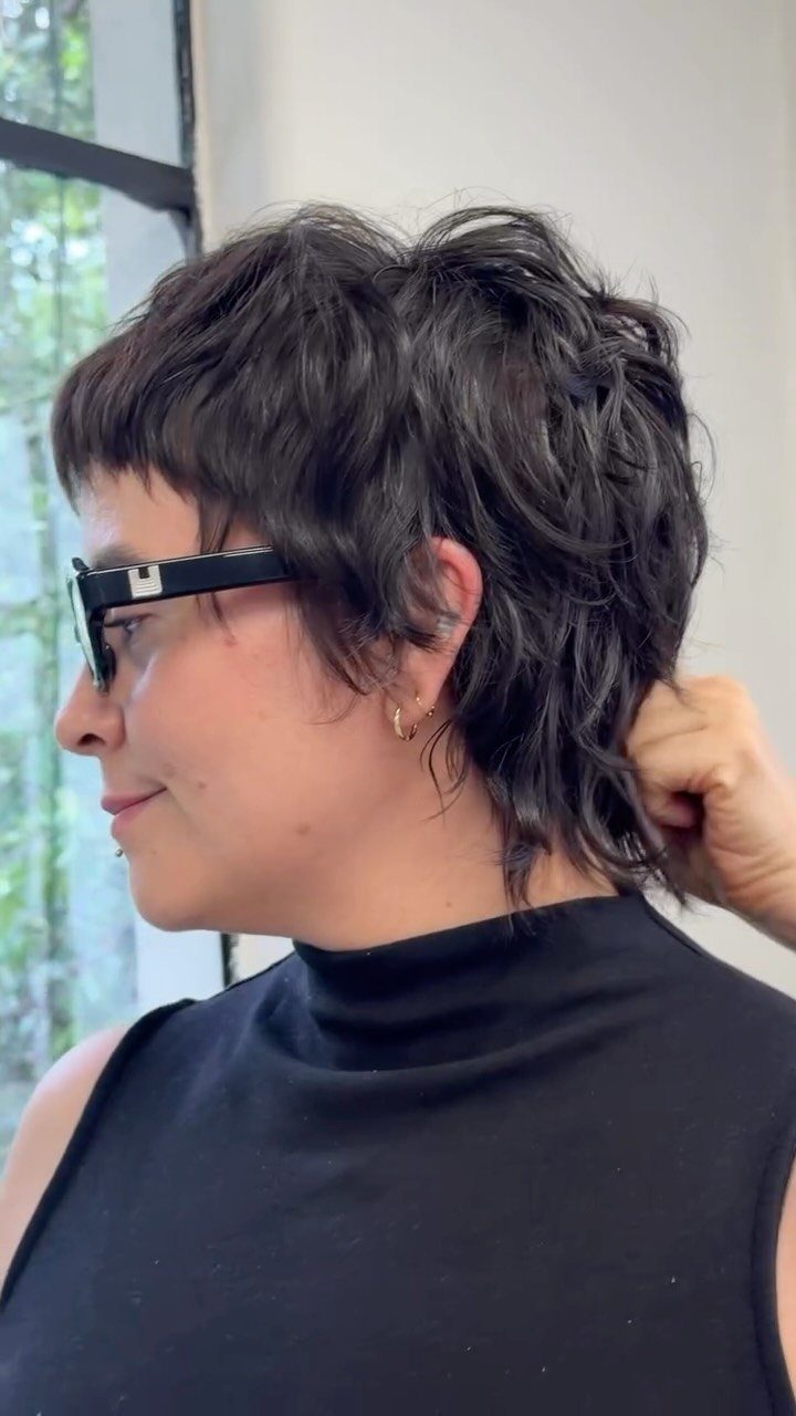 Short dark shag with wispy bangs and face-framing layers on a person in profile
