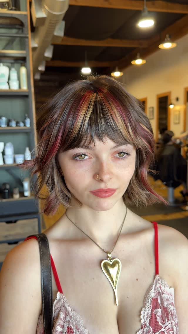 Woman showing a short layered shag with reddish highlights and bangs
