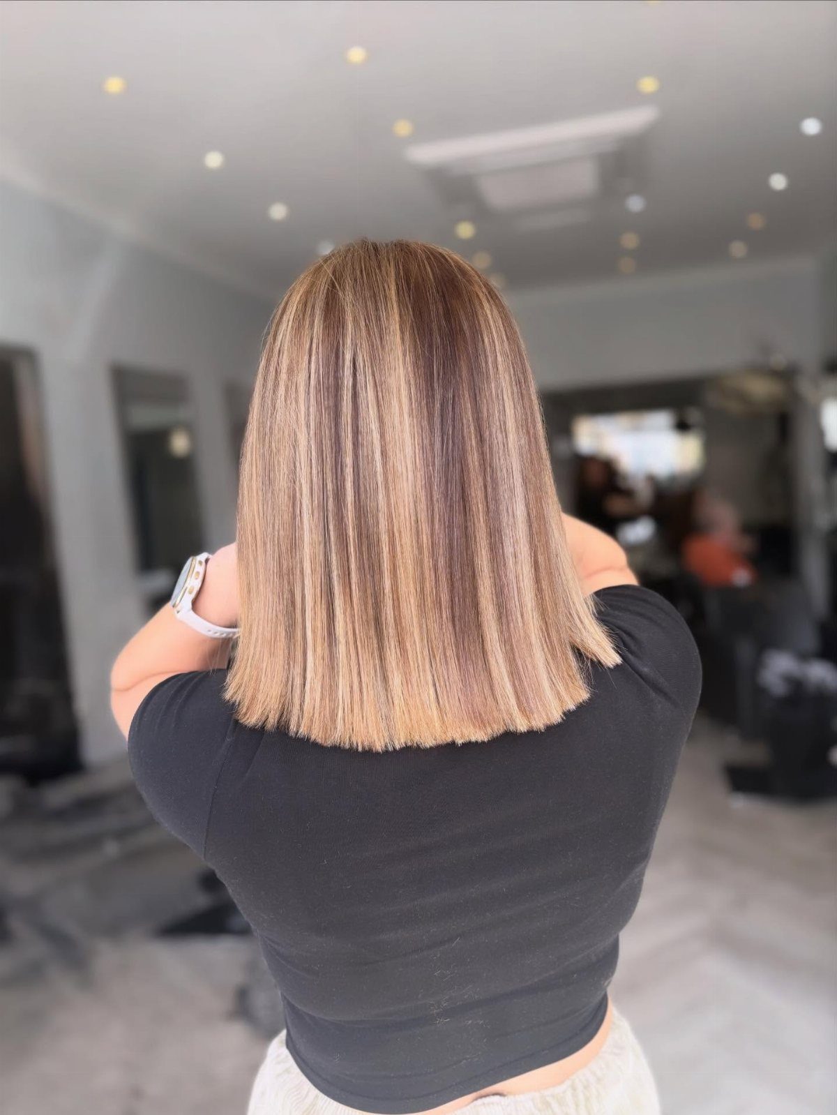 Blunt shoulder-length bob with straight light brown hair in a salon